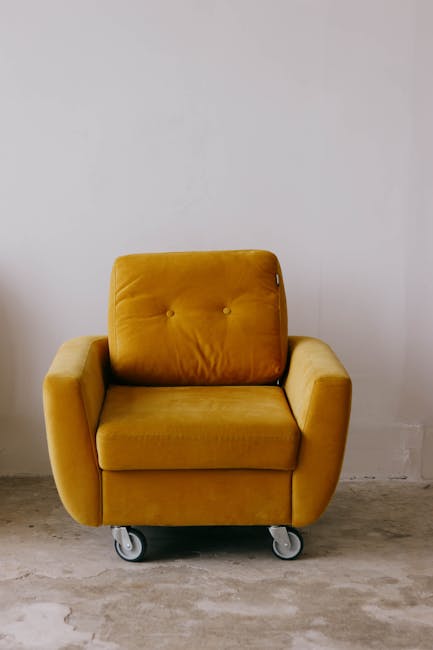 A close-up view of a tan leather sofa in a living room, showing smooth, clean surfaces with tufted cushions and visible stitching. The sofa's surface appears polished and dust-free, contributing to a 